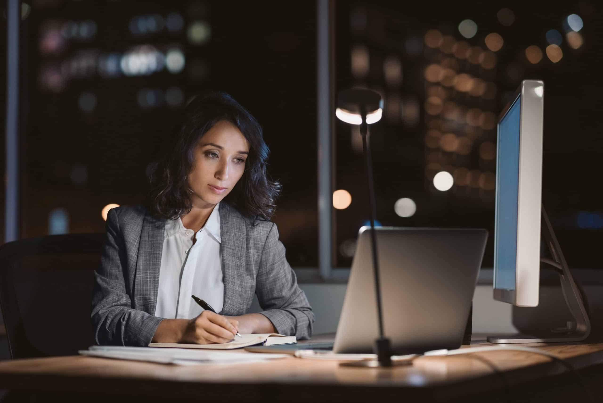 Female private investigator working late at night on laptop for F3 Private Investigations.