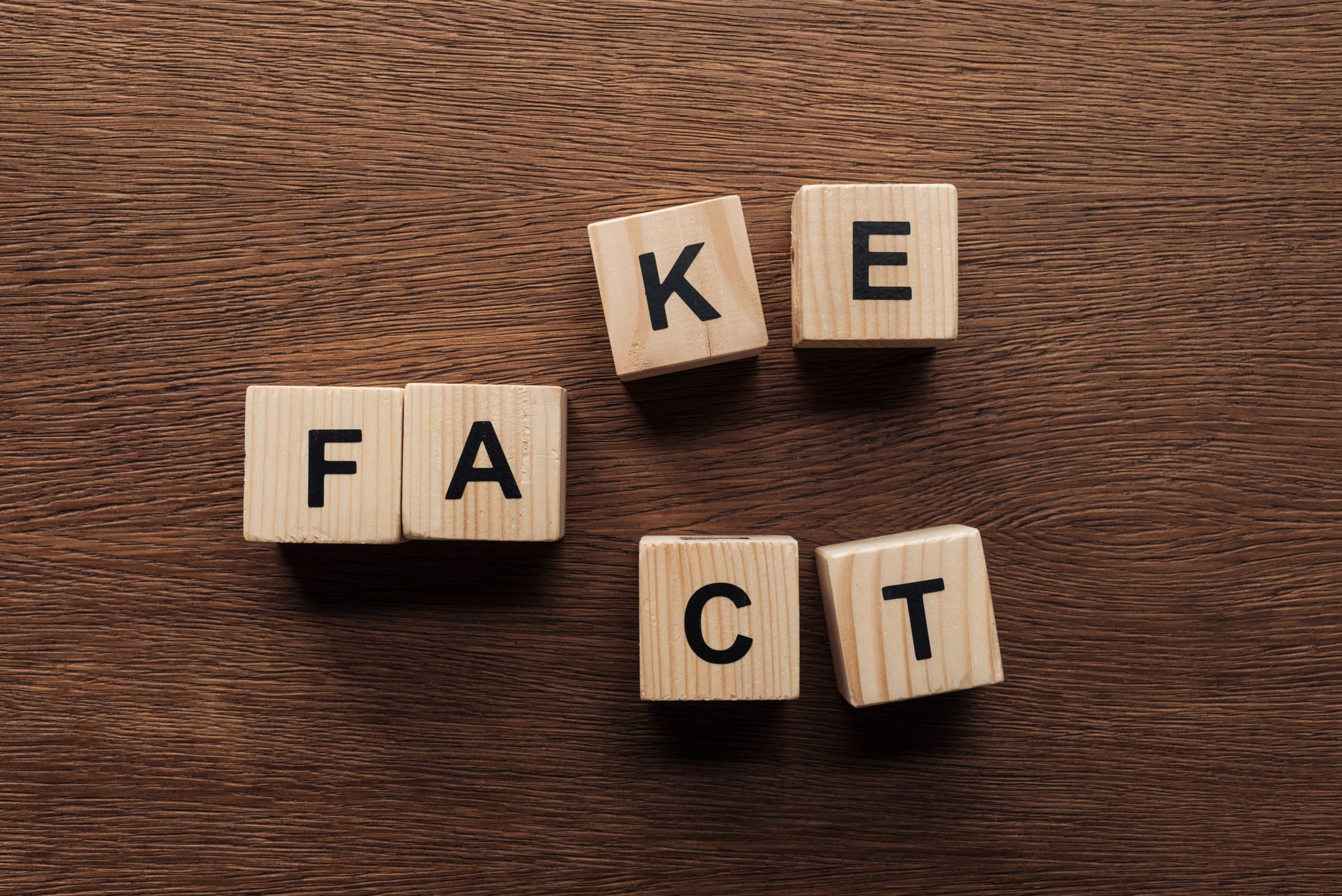 Wooden cubes with 'FAKE' and 'FACT' letters