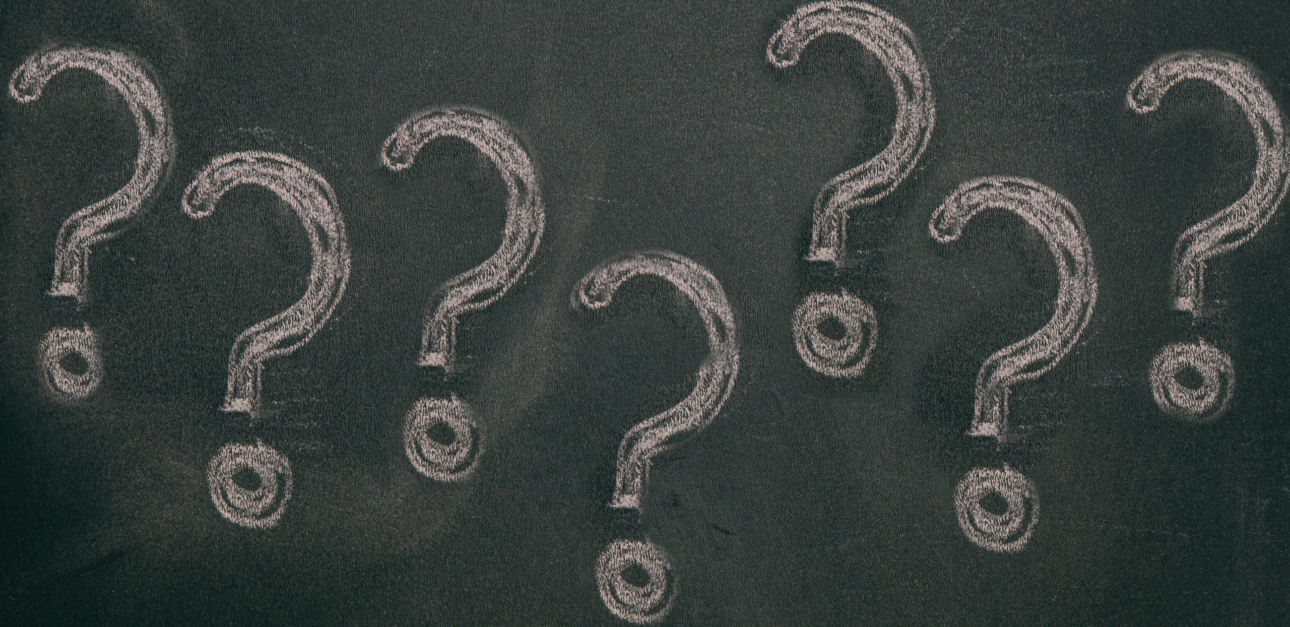 Chalk question marks on a blackboard.