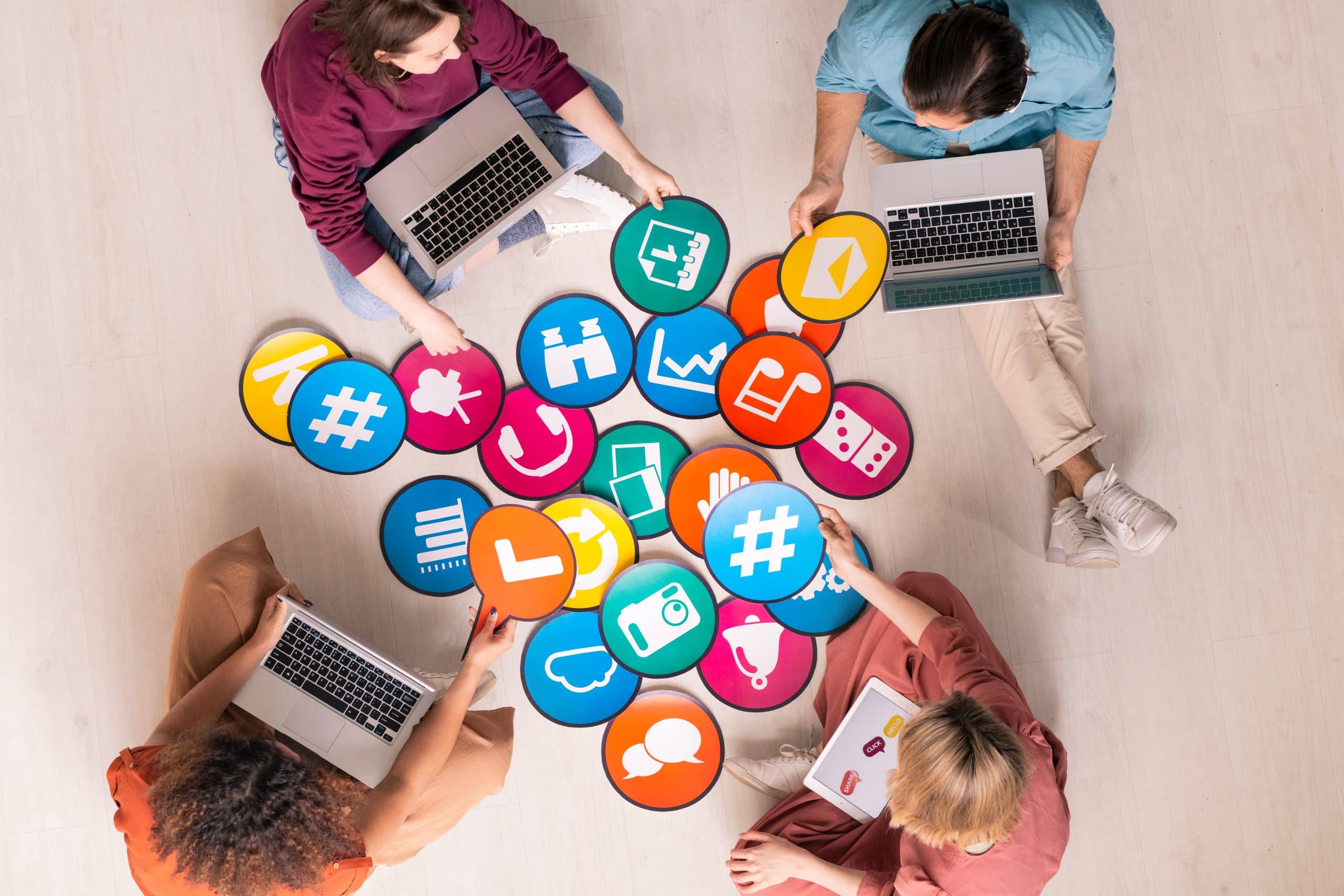 People using laptops with social media icons on floor.