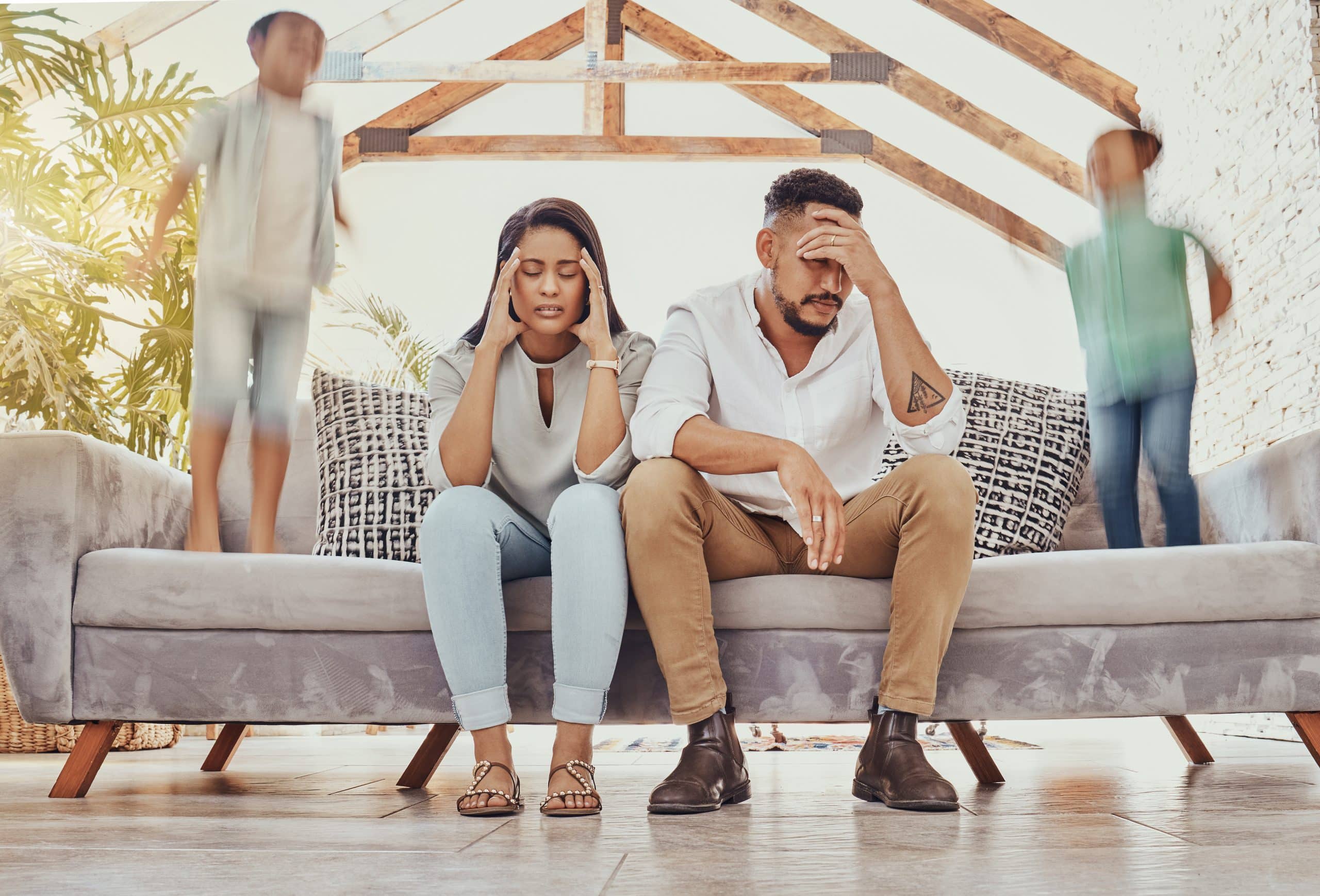 Stressed couple with energetic kids indoors